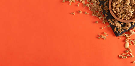 Muesli cereals and almonds on slate tray and cork bowl on orange background. Flat lay. Copy space.の写真素材