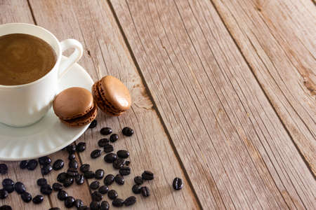 French macarons dessert with coffee cup and coffee beans. Copy space. Selective focus.