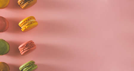 French pastel colored macarons dessert on pink background. Copy space. Selective focus.の写真素材