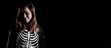 Young woman smiling dressed as a halloween skeleton. Night of the dead. Copy space. Selective focus.の写真素材