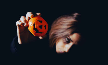 Woman in halloween skeleton costume with toy pumpkin. Night of the dead. Copy space. Selective focus.の写真素材