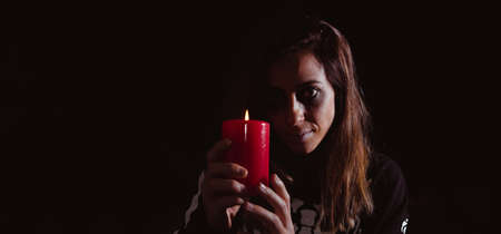 Dark woman holding a candle on halloween. Night of the dead. Copy space. Selective focus.の写真素材