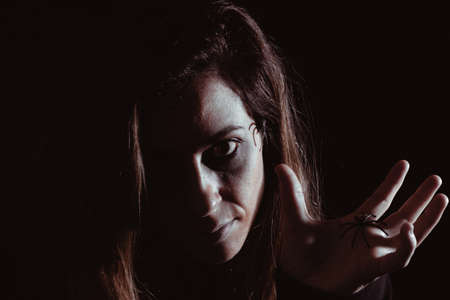 Woman with halloween spiders all over her face. Night of the dead. Copy space. Selective focus.の写真素材