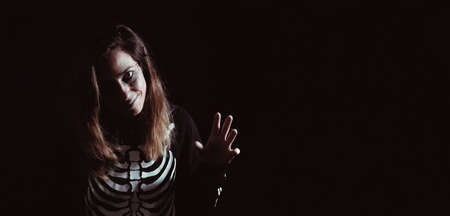 Young woman in halloween skeleton costume. Night of the dead. Copy space. Selective focus.の写真素材