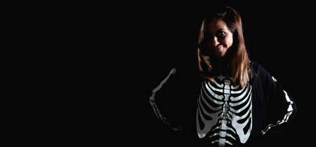 Young woman smiling dressed as a halloween skeleton. Night of the dead. Copy space. Selective focus.の写真素材