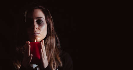 Dark woman holding a candle on halloween. Night of the dead. Copy space. Selective focus.の写真素材