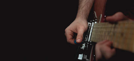 Person plucking the strings of an electric guitar with a pick. Selective focus. Copy space.の写真素材