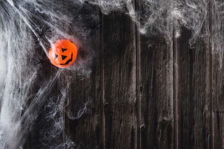 Spider web on wooden background with toy halloween pumpkin. Copy space. Selective focus.の写真素材