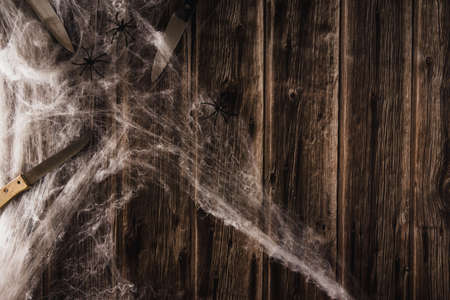 Spider web on wooden background with knives. Halloween banner. Copy space. Selective focus.の写真素材