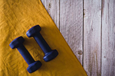 Fitness dumbbells with towel on wooden background. Gym accessories. Copy space. Selective focus.の写真素材