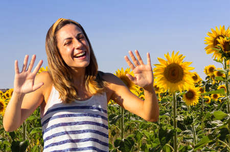 Portrait of young woman smiling in a field of sunflowers. Sunny day. Copyspace. Selective focus.の写真素材