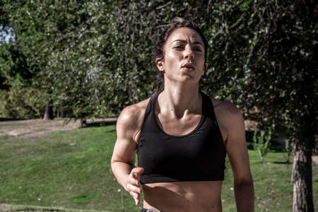 Young woman running through a park on a sunny day. Healthy lifestyle. Selective focus.の写真素材