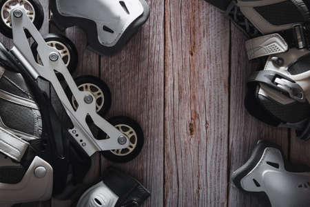 Inline skates with knee and elbow pads on wooden background. Roller. Copyspace. Selective focus.の写真素材