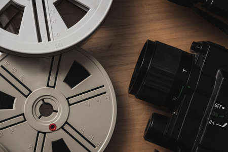 Old 8mm video camera with film reels on wooden background. Copy space. Selective focus.