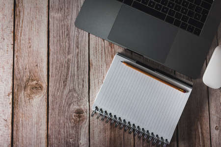 Workspace with laptop, notebook and pencil on wooden background. Top view. Copyspace. Selective focus.の写真素材