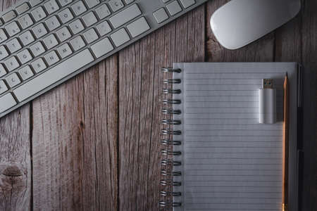 Workspace with computer keyboard, mouse, notebook and USB flash drive on wooden background. Top view. Copyspace. Selective focus.の写真素材