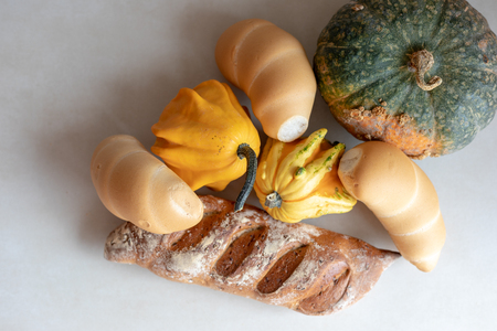 Bread and whole grain bread and autumn pumpkins on textured light backgroundの写真素材