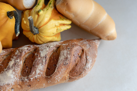 Bread and whole grain bread and autumn pumpkins on textured light backgroundの写真素材