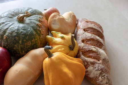 Bread and whole grain bread and autumn pumpkins on textured light backgroundの写真素材