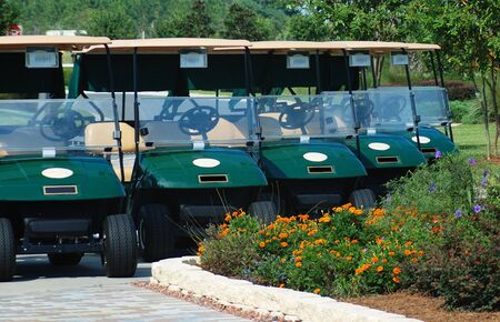 five green golf carts in a line.の写真素材