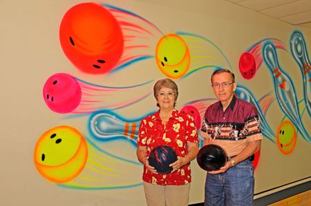 Two bowlers with bowling balls against a colorful wall at the alley.の写真素材