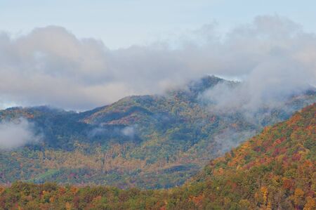 Clouds hovering over the Smoky Mountain top in early morning muting the Fall foliage.の写真素材