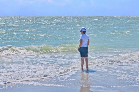 Woman wading in the surf to cool off on a hot day の写真素材