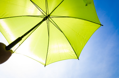 Green umbrella in sunny day with blue sky backgroundの写真素材