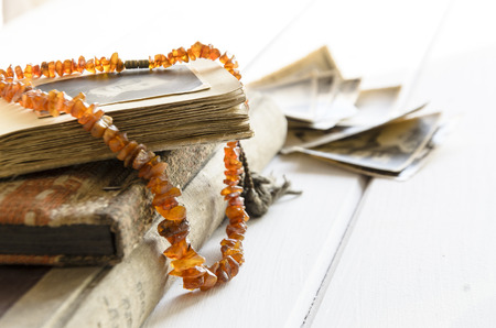 Stack of old photographs with amber necklace on photo albumの写真素材