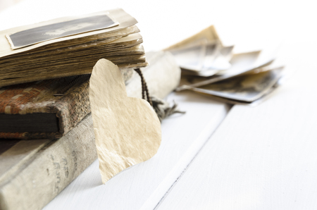 Stack of old photographs and photo album and heart shapeの写真素材