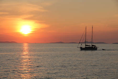 Sunset over the sea with sail boatの写真素材