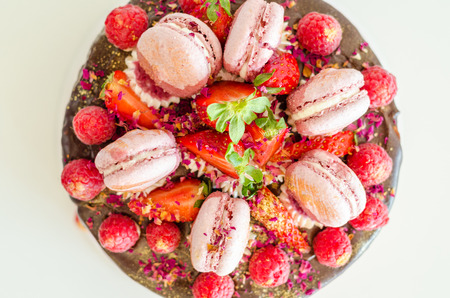 Birthday chocolate cake with strawberries, raspberries and macarons.の写真素材