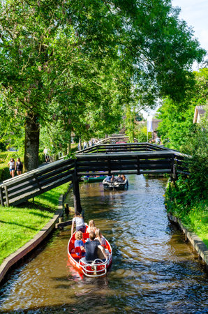 Giethoorn, Netherlands - July 17,2016: Tourists on a boat trip on the canals between the rustic thatched roof houses in the famous village of Giethoorn from Netherlands.のeditorial素材