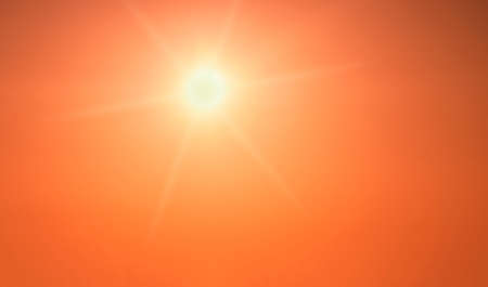 The sun shining brightly in a clear orange skyの写真素材