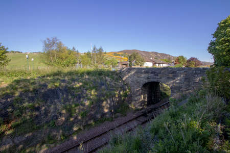 A stone bridge spanning a single railway track in Helmsdale, Scottish Highlands, UK