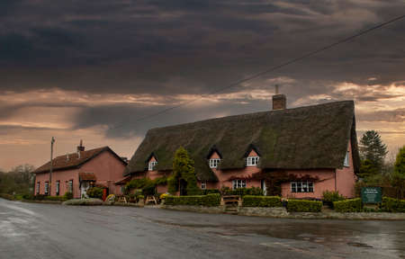 Dark clouds over the Four Horseshoes pub in Thornham Magna, Suffolk, UKのeditorial素材