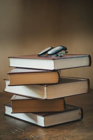 A pile of books with glasses on a table.の写真素材