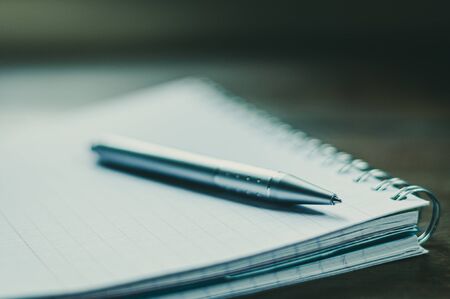 Ball point pen on spiral note pad.,posed on wooden desk,selective focus.の写真素材
