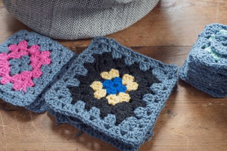 hand made crochet granny squares on wooden table.