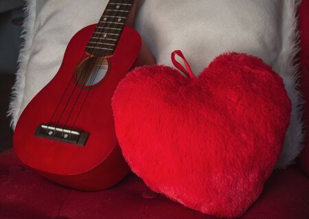 ukulele on chair with red heart cushion  concept I love music ,cosy warm weekend.の写真素材