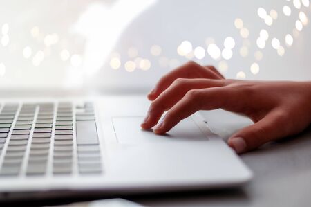 hand on laptop computer trackpad ith bokeh background. room for text. backdrop.