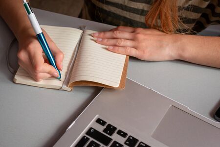 Young woman working at home, Student girl writing in note pad & looking at computer , online shopping, work or studying from home, freelance, online learning, distance education conceptの写真素材