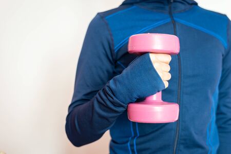 Young woman  working out at home with pink weights, on white background. sport & keeping fit.