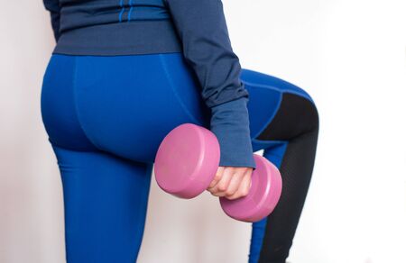 Young woman  working out at home with pink weights, on white background. sport & keeping fit.