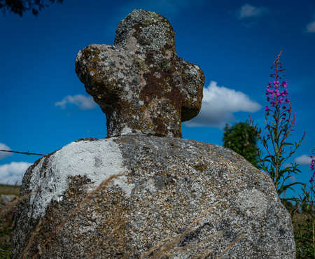 Rustic stone cross against a blue sky, Lozere, France.の写真素材
