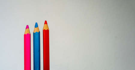 pink, blue, and red pencils isolated on white background, minimalist backdrop wih room for text.の写真素材