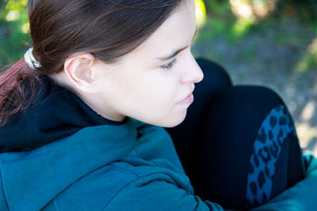 young woman, teenager sitting outside, deep in thought, relaxing.の写真素材