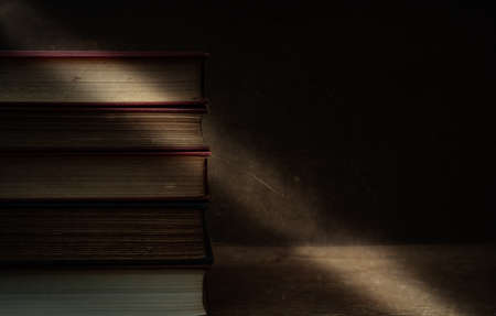 old books stacked up on table, moody with room for text, concept of time passsing.