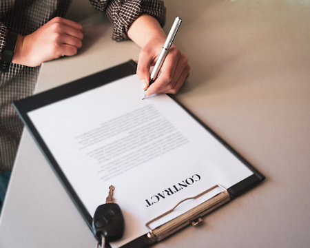 man signing contract for care hire or buying a new car. with car keys, selective focus.の写真素材