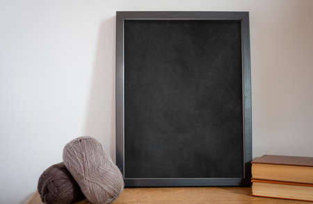 mock up blackboard or chalkboard with balls of wall and books on wooden table, concept knitting or...